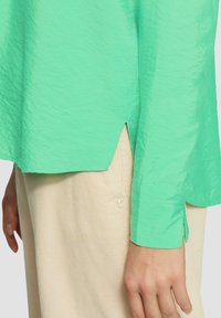 Lichtgewicht, gekreukt mintgroen shirt met omgeslagen manchetten en een hoge-laag zoom. Gepaard met beige corduroy broeken met een klein logo.