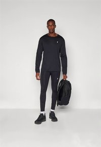 Black long-sleeve shirt, matching leggings, and black sneakers, with a black backpack. Simple design, smooth texture, and fitted shape.