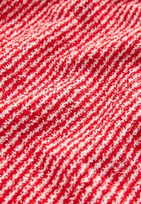 Gros plan sur un tissu tricoté texturé rouge et blanc avec un motif à rayures horizontales.