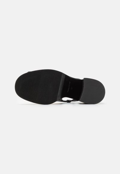 Black sole of a women's dress shoe with a textured front half and smooth rounded heel on a white background.