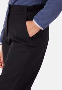 Svarta byxor med en mjuk och slät textur samt vertikala sömmar. Har en sidoficka och kardborreknäppning i midjan.