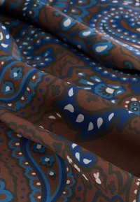 Baumwollstoff mit braunem Grund, der filigrane blaue und weiße Paisley-Muster, eine glatte Textur und lebendige kontrastreiche Farben aufweist.