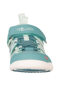 Shoe infantil turquesa com parte superior em malha respirável, faixa ajustável e sola de borracha branca. Apresenta uma bandeira norueguesa vermelha na lateral.