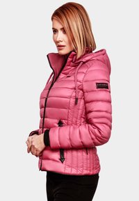 Roze pufferjas met kap, voorzien van een geborduurd ontwerp, zwarte accenten, ritssluitingen in de zakken en trekkoorden aan de kap en onderrand.