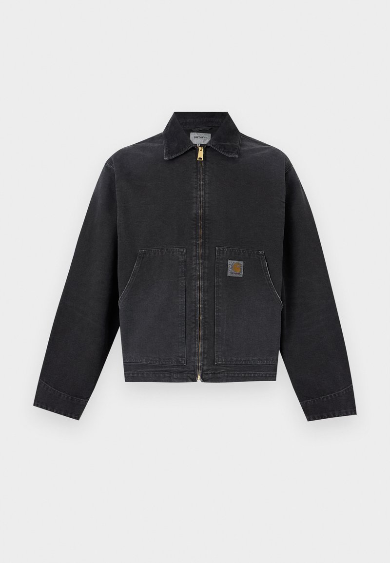 Schwarze Reißverschlussjacke mit spitzem Kragen, zwei Fronttaschen, davon eine mit kleinem braunem Logo-Patch, langen Ärmeln und geradem Saum.