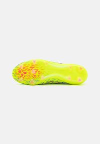 Suela de zapato en un amarillo brillante con una superficie texturizada, que presenta patrones multicolores y múltiples tacos para tracción.