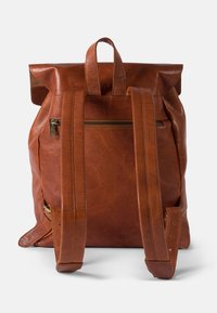 Brown leather backpack with a roll-top closure, two padded straps, and a front zip pocket. Textured surface with visible stitching details.