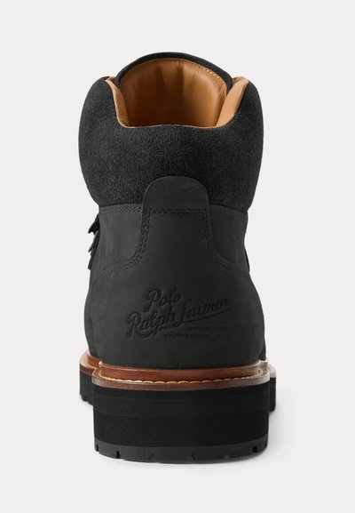 Achteraanzicht van een zwarte Polo Ralph Lauren enkellaars met bruine leren voering en dikke zool op een witte achtergrond.