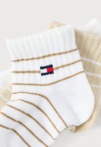 Καλσόν με λευκές και μπεζ ρίγες και ριμπ μανσέτες, με μικρό λογότυπο σε κόκκινο, λευκό και μπλε. Μαλακή υφή; υλικό μείγματος βαμβακιού.