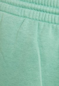 Muntgroene stof met een soepele textuur. Heeft een elastische tailleband en stikseldetails, die een ontspannen pasvorm en lichtgewicht materiaal benadrukken.