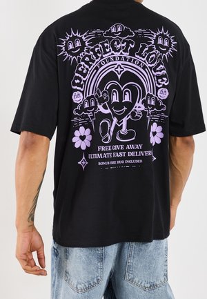 Zwart T-shirt met paarse afbeelding van een lachend hartfiguur, zon en wolken, bloemen, en tekst met de woorden "Perfect Love Foundation" en details over een weggeefactie.