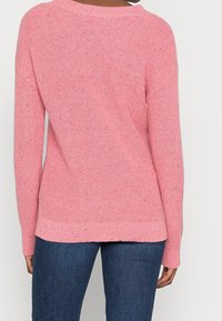 Pull en maille rose à coupe ample, col rond et manches longues. Présente un motif texturé avec des touches de couleur disséminées partout.