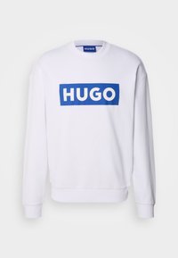 Biały dres z długimi rękawami, z niebieskim prostokątnym logo z napisem "HUGO" w białym kolorze z przodu. Gładka tekstura.