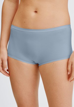 Femme portant un shorty bleu clair sans couture, montré de la taille jusqu'en haut des cuisses sur un fond neutre.