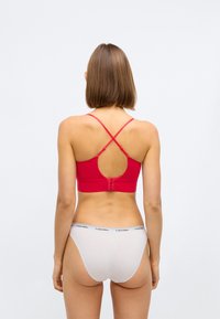 Rode sportbh met verstelbare kruisbanden en een keyhole rugontwerp. Gecombineerd met witte onderkleding met een zwarte logoband.