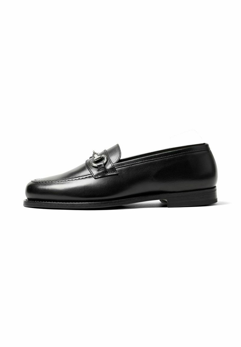 Black leather loafer with a smooth surface, slightly rounded toe, decorative strap, and a low, rectangular heel.