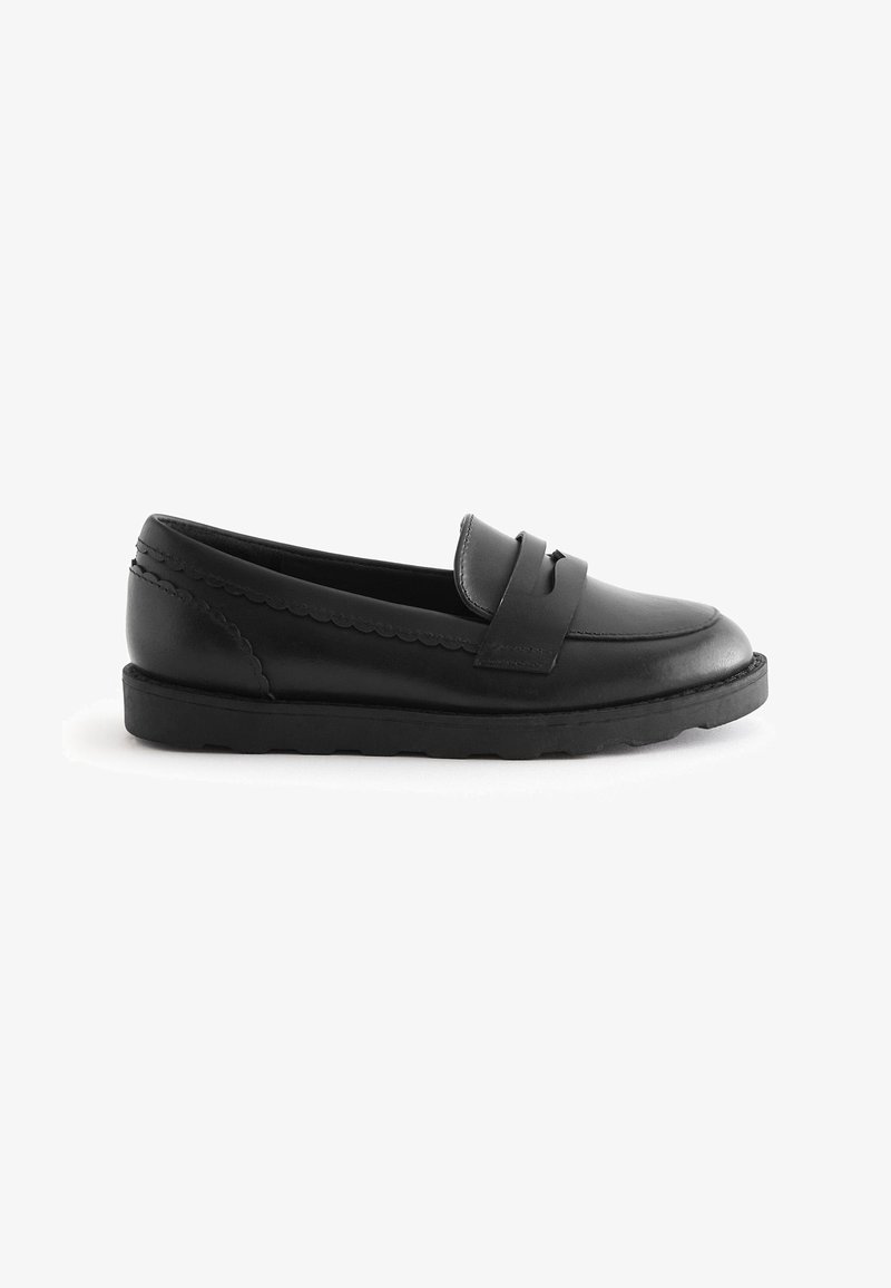 Mocassin en cuir noir avec une semelle en caoutchouc basse, un bord festonné décoratif et une lanière sur le dessus avant.