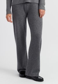 Grijze wollen wijde broek, zachte textuur, mid-rise taille, gecombineerd met zwarte loafers. De stof lijkt dik en warm, met een gladde afwerking.