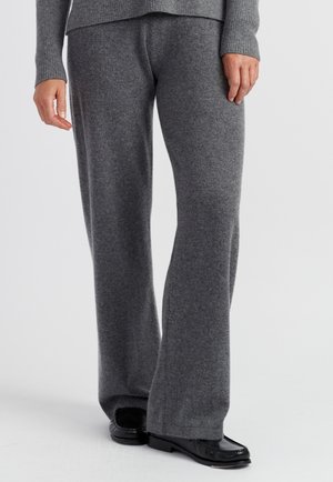 Graue Woll-Hose mit weitem Bein, weiche Textur, mittelhoher Bund, kombiniert mit schwarzen Slippern. Der Stoff wirkt dick und warm, mit einer glatten Oberfläche.
