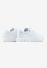 Zapatillas blancas de cuero liso, con un diseño de caña baja, punta redondeada y suela de goma plana. Logo grabado en el talón.
