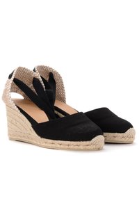 Černé espadrilky na platformě s tkanou jutovou podrážkou, otevřenou patou a překříženými pásky vyrobenými z texturovaného béžového materiálu.