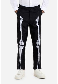 Black pants with printed white skeletal bone design along the legs. Made from a smooth material; features a button closure and pockets.