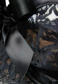 Black lace fabric with a satin ribbon. The texture features intricate mesh patterns and a smooth, glossy finish on the ribbon.