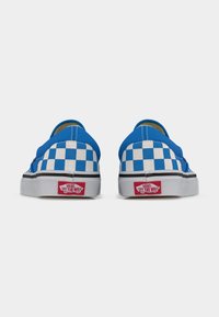 Ζευγάρι slip-on αθλητικών παπουτσιών Vans με μπλε και λευκό καρό μοτίβο, σε θέα από πίσω, με κόκκινες λογότυπες "Off The Wall" σε λευκές σόλες.