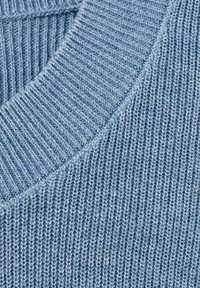 Světlounce modrá pletená látka se žebrovanou strukturou, s kulatým výstřihem a hladkým okrajem. Rovnoměrně prošitá a působící měkce.