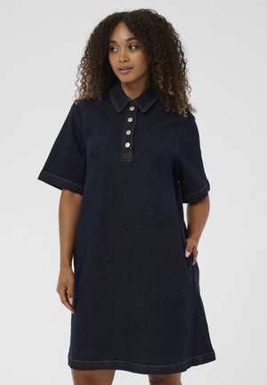 Tumši zilas džinsa krekla kleita ar apkakli, īsām piedurknēm, piecu pogu aizdari un sānu kabatām; izceļ kontrastējošas šuves.