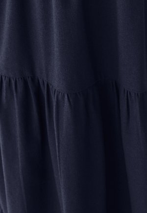 Tmavomodrá látka s nariasenými švami vytvárajúcimi jemné vertikálne záhyby a textúru.