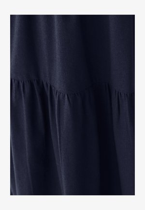 Ciemnoniebieski materiał z detalami w postaci marszczonych szwów, tworzącymi miękkie pionowe fałdy i teksturę.