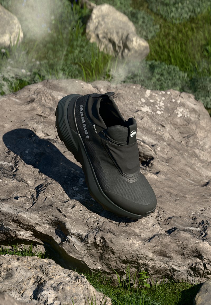 Čierna turistická obuv s textúrovaným zvrškom, elastickým golierom a výrazným logom. Vyznačuje sa robustným dizajnom podrážky pre stabilitu na skalnatom teréne.
