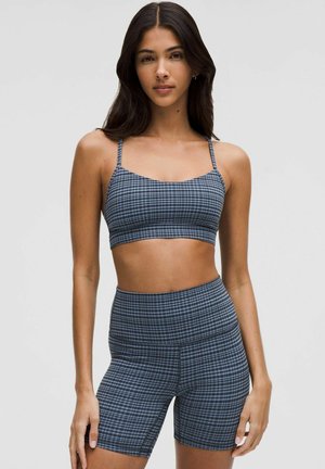 Conjunto deportivo de cuadros azules que presenta un top corto con tirantes finos y pantalones cortos de cintura alta, fabricado en un tejido liso y elástico.