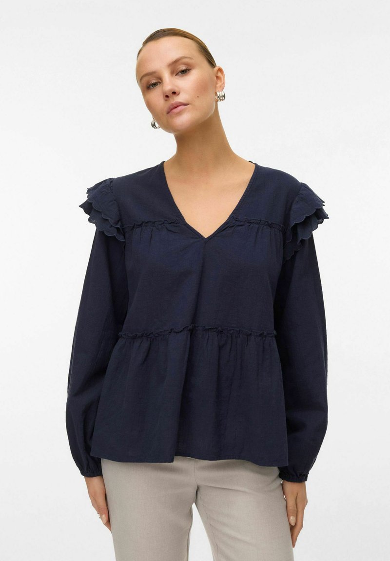 Blusa blu navy con scollo a V, maniche lunghe e dettagli arricciati sulle spalle. Design a strati con texture arricciata e vestibilità comoda.