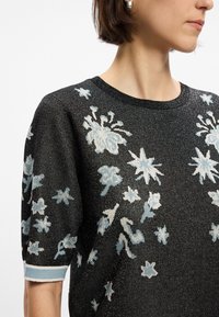 Μαύρος πλεχτός σκούφος με ελαφριά μπλε λουλούδια και αστέρια, κοντό μανίκι και rib κολάρο με μπλε λεπτομέρεια.