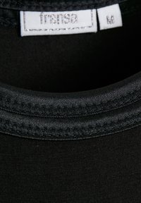 Collo di t-shirt in tessuto nero con una texture liscia. Presenta un'etichetta cucita con "fransa" e la taglia "M" con cuciture bianche e argento.