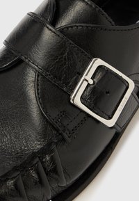 Must nahast king hõbedase ruudukujulise pandla ja detailse õmblusega valgel taustal.