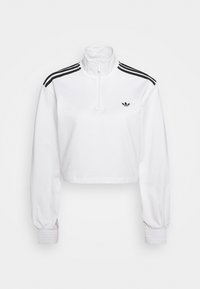 Biała krótka bluza na zamek z długim rękawem, z czarnym logo Adidas trefoil na piersi oraz trzema czarnymi paskami na ramionach i rękawach.