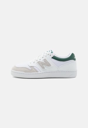 Weißer und grüner New Balance Low-Top-Sneaker mit beigen Wildlederakzenten und Logo an der Seite, von der Außenseite betrachtet.
