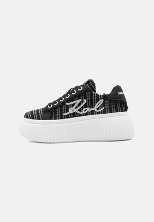 Zwarte geruite sneaker met dikke witte geribbelde plateauzool, witte "Karl" borduring aan de zijkant en rafelige stofranden.