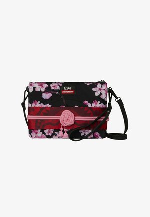 Bolso bandolera negro con estampado de florecillas de cerezo en rosa, banda roja y nudo decorativo rosa con borlas, con una correa negra desmontable.