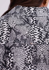 Black and white patterned fabric featuring a mix of spots and textures. Includes a visible tag with "MABALUC" on the back.