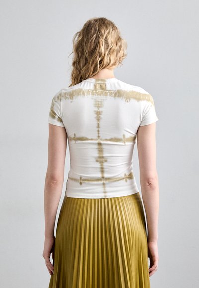 Hvit kortermet t-skjorte med beige tie-dye mønstre og logo på øvre rygg, sammen med et plisserte olivengrønt skjørt.