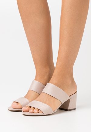 Sandales à talons block en daim rose clair, dotées de large sangles sur les orteils et la cheville, avec une finition lisse et texturée.