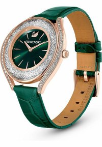 Uhr mit grünem Lederarmband, rundem Gehäuse aus Roségold, glitzerndem Kristallrand und dunklem grünen Zifferblatt, das metallische Indizes und Zeiger aufweist.