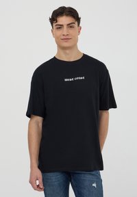 T-shirt di cotone nero con maniche corte e collo rotondo, con la scritta "WEST COAST" stampata in bianco sul petto.