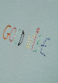 Jasnoniebieska tkanina z wyszytym napisem "DOBRE WIBRACJE" w wielu kolorach: pomarańczowym, różowym, czarnym, zielonym, żółtym i niebieskim. Gładka faktura.