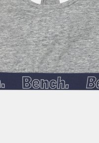 Grå stofftank topp med en bred marineblå kant nederst, med hvit "Bench." tekst. Jevn tekstur med rund hals.