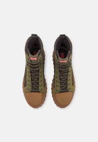 Sneakers alte marroni e verdi con accenti testurizzati, dotate di un colletto imbottito, lacci e una soletta con marcatura ben visibile.